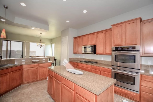 kitchen with light tile patterned flooring, hanging light fixtures, a kitchen island, stainless steel appliances, and a chandelier