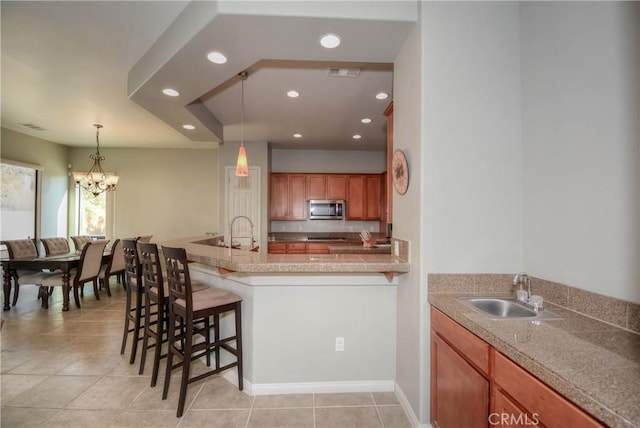 kitchen featuring a notable chandelier, light tile patterned floors, sink, and a breakfast bar area