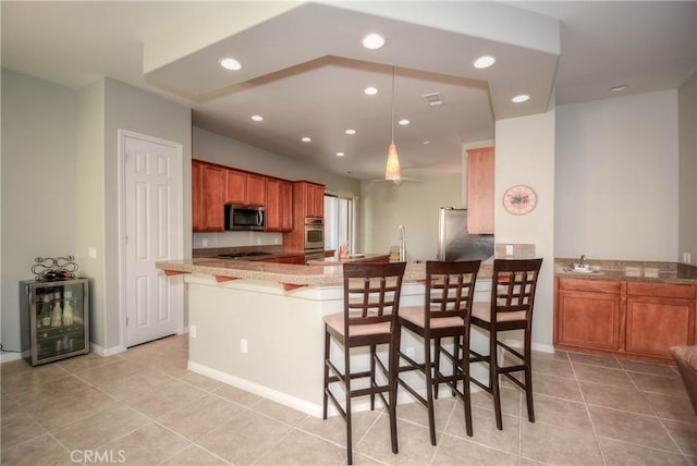 kitchen featuring a breakfast bar, light tile patterned floors, kitchen peninsula, and appliances with stainless steel finishes