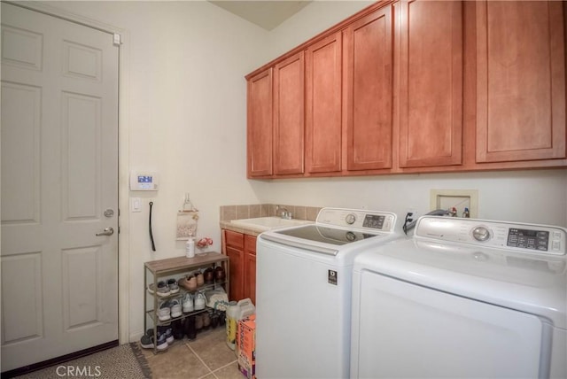 laundry area with washer and clothes dryer, cabinets, light tile patterned floors, and sink