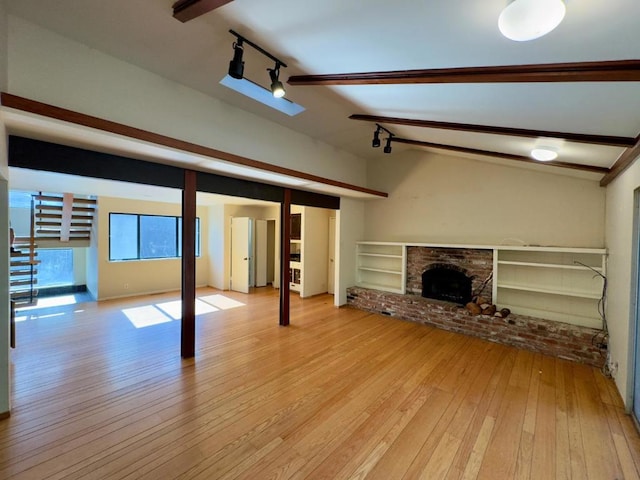 unfurnished living room featuring lofted ceiling with beams, a fireplace, and light hardwood / wood-style flooring