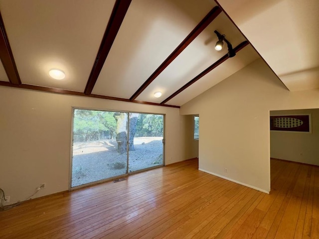 unfurnished living room featuring vaulted ceiling with beams and light hardwood / wood-style floors