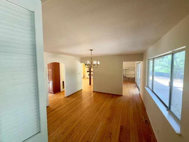 spare room with an inviting chandelier and light hardwood / wood-style flooring