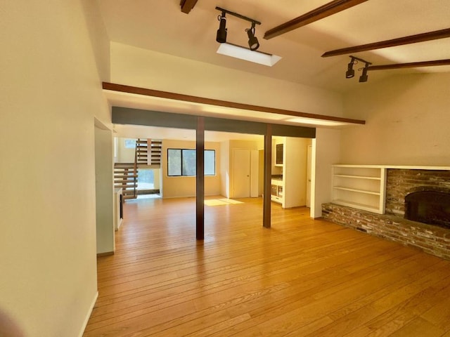 unfurnished living room featuring light hardwood / wood-style flooring, beamed ceiling, and a fireplace