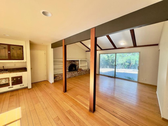 unfurnished living room with hardwood / wood-style flooring, sink, lofted ceiling with beams, and a fireplace