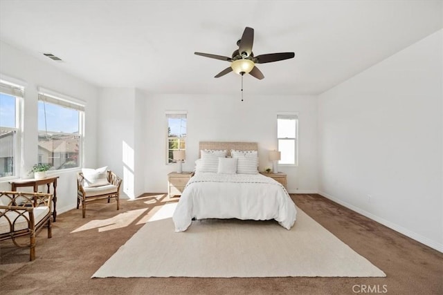 carpeted bedroom with multiple windows and ceiling fan