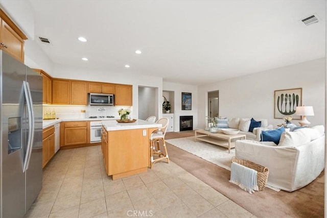 kitchen featuring a kitchen breakfast bar, a kitchen island, light tile patterned floors, and stainless steel appliances