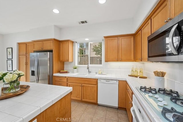 kitchen featuring tile counters, light tile patterned floors, sink, and appliances with stainless steel finishes