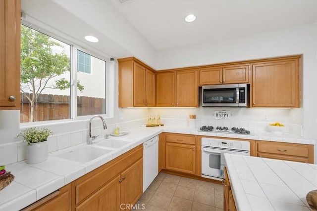 kitchen with tile counters, light tile patterned flooring, white appliances, and sink