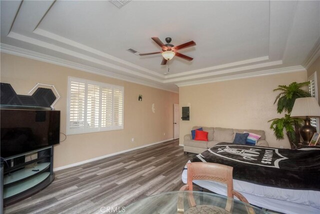 living room featuring ceiling fan, a raised ceiling, wood-type flooring, and ornamental molding