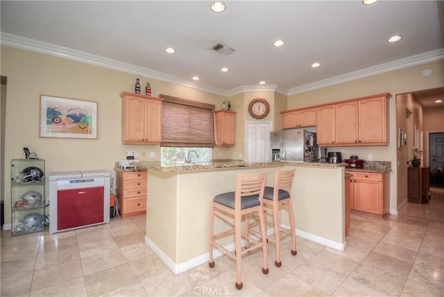 kitchen with a kitchen bar, stainless steel fridge with ice dispenser, crown molding, and a kitchen island