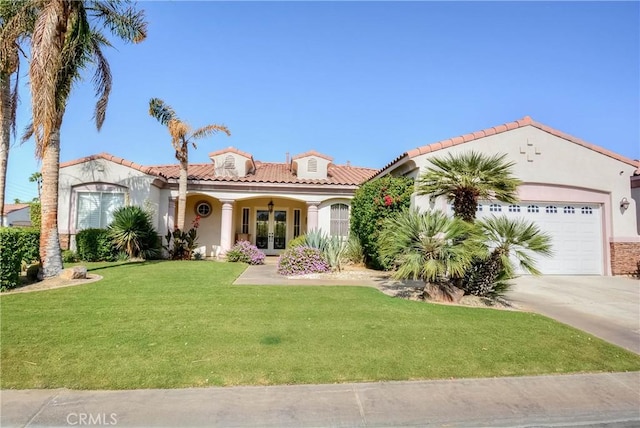 mediterranean / spanish-style home featuring a garage, a front yard, and french doors