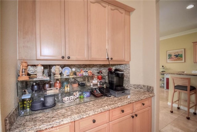 interior space featuring light stone countertops, light brown cabinets, tasteful backsplash, light tile patterned flooring, and ornamental molding