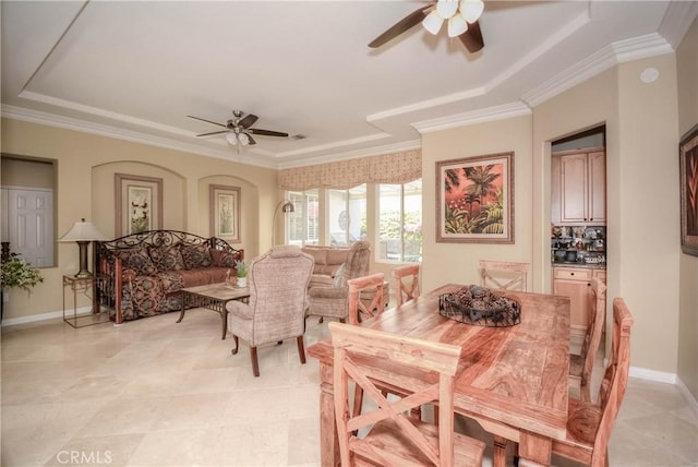 dining room with a raised ceiling, crown molding, and ceiling fan