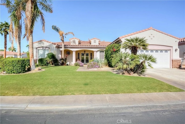 mediterranean / spanish house with french doors, a garage, and a front lawn