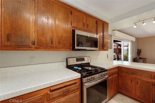 kitchen with rail lighting, stainless steel appliances, and light tile patterned floors