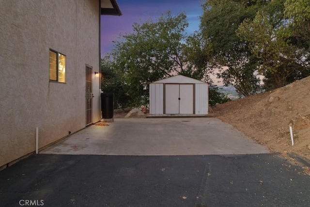 yard at dusk featuring a storage shed