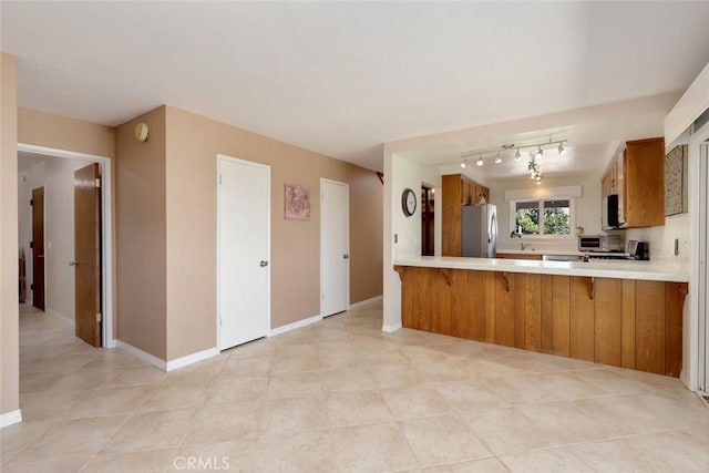 kitchen with stainless steel fridge, kitchen peninsula, rail lighting, and light tile patterned floors