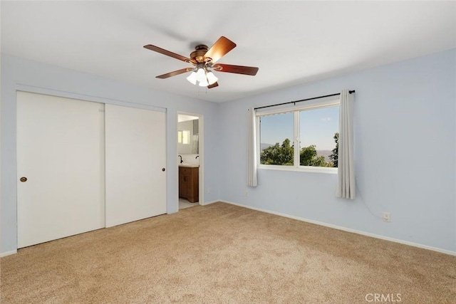 unfurnished bedroom with light carpet, a closet, ensuite bath, and ceiling fan