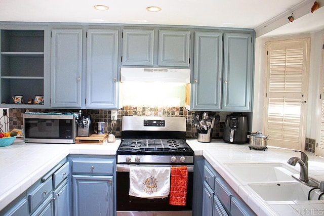 kitchen featuring appliances with stainless steel finishes, decorative backsplash, tile counters, and sink