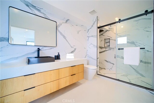 bathroom featuring toilet, vanity, and a shower with door