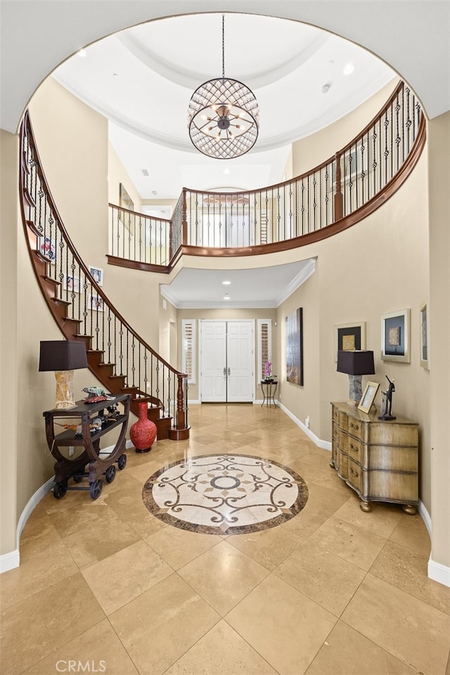 foyer entrance featuring a towering ceiling and crown molding