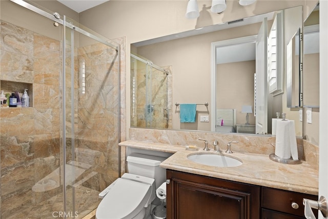 bathroom featuring vanity, toilet, and a shower with shower door