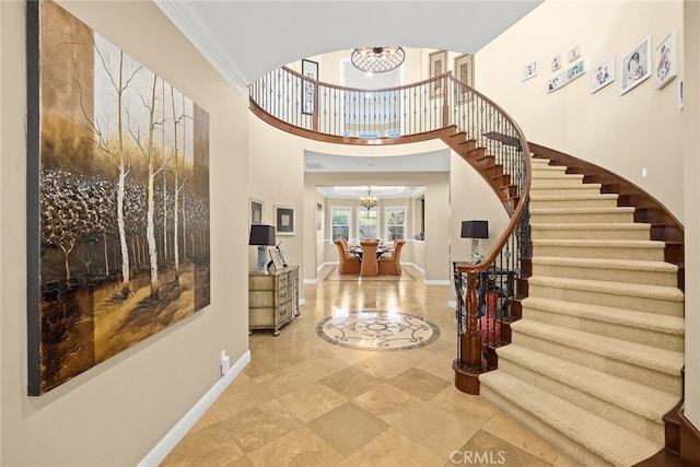 foyer featuring crown molding, a chandelier, and a high ceiling