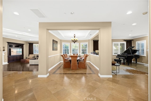 dining space with crown molding, a raised ceiling, a wealth of natural light, and an inviting chandelier