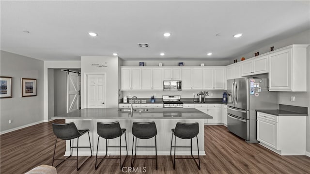 kitchen featuring stainless steel appliances, sink, a barn door, and white cabinets