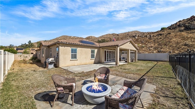 back of house featuring a yard, an outdoor fire pit, a mountain view, and a patio