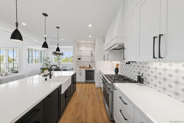 kitchen featuring white cabinets, wine cooler, decorative light fixtures, and high end range