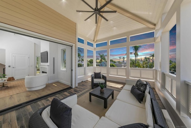 sunroom / solarium featuring a healthy amount of sunlight, lofted ceiling with beams, wooden ceiling, and ceiling fan