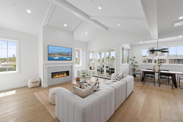 living room featuring plenty of natural light, beamed ceiling, light wood-type flooring, and a fireplace