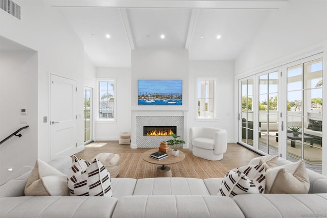 living room with beamed ceiling, a fireplace, high vaulted ceiling, and light wood-type flooring