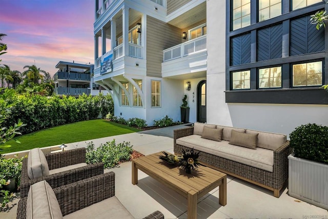 patio terrace at dusk with a balcony and an outdoor living space