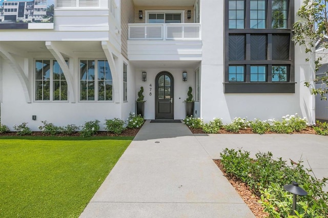 entrance to property featuring a balcony and a yard