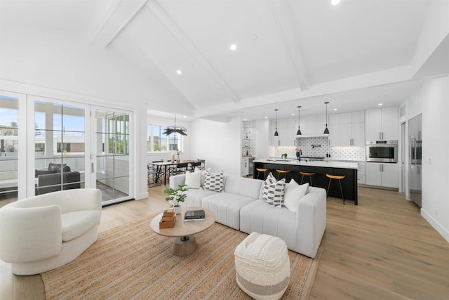 living room with vaulted ceiling with beams and light wood-type flooring