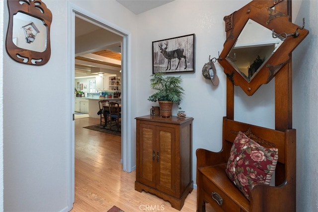 hallway featuring beam ceiling and light hardwood / wood-style flooring