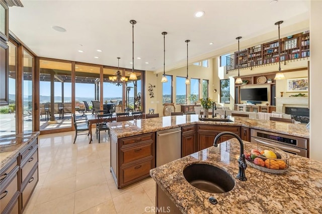 kitchen with decorative light fixtures, sink, stainless steel oven, and light stone counters