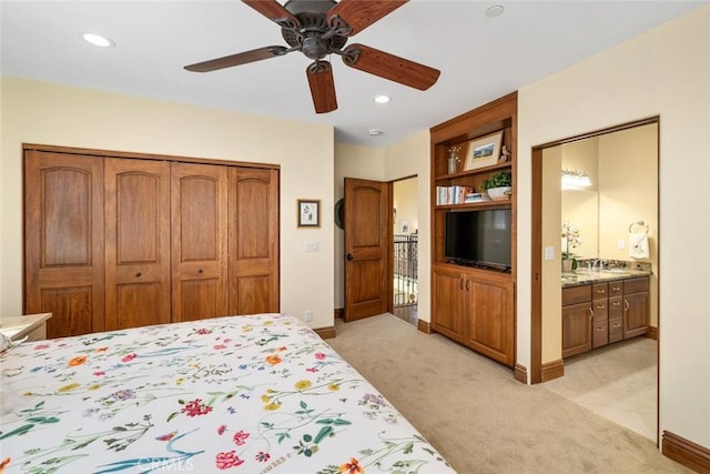 bedroom featuring ceiling fan, a closet, light colored carpet, and ensuite bath