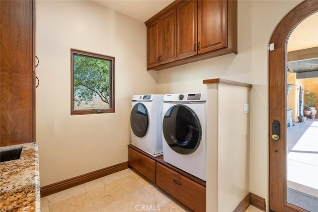 laundry area with washing machine and clothes dryer and cabinets