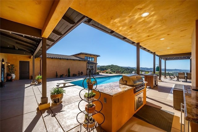 view of swimming pool with a mountain view, a diving board, a grill, and a patio