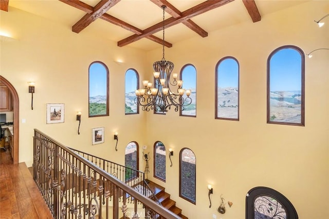 hallway with a chandelier, a wealth of natural light, beamed ceiling, and coffered ceiling