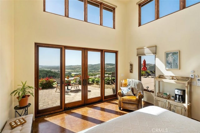 bedroom with french doors, access to exterior, a mountain view, and a towering ceiling