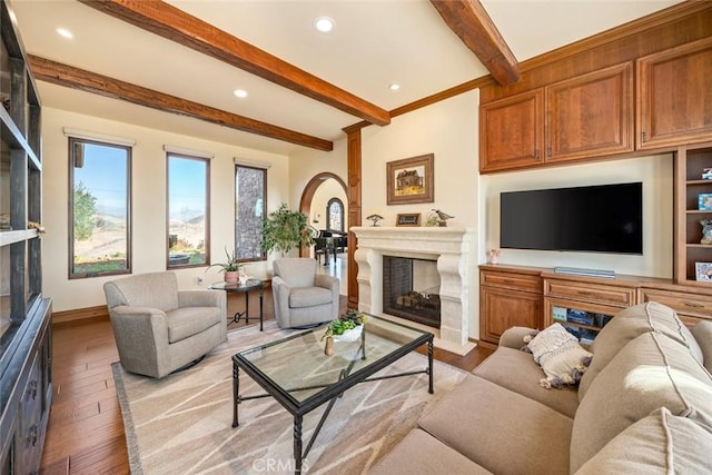 living room with beam ceiling, light wood-type flooring, and a fireplace