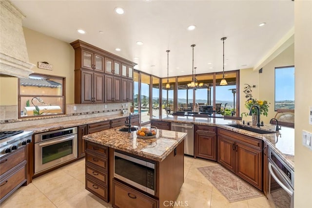 kitchen featuring pendant lighting, appliances with stainless steel finishes, a center island, decorative backsplash, and sink