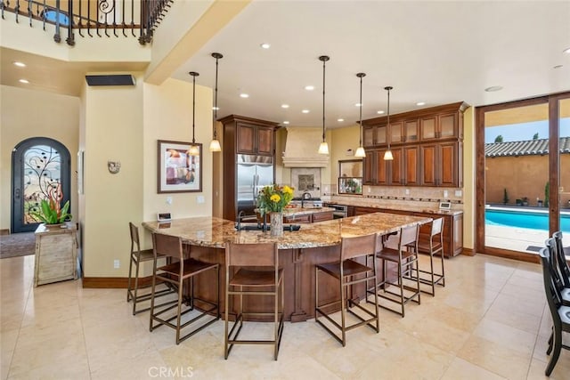 kitchen featuring pendant lighting, stainless steel appliances, backsplash, light stone counters, and a breakfast bar area