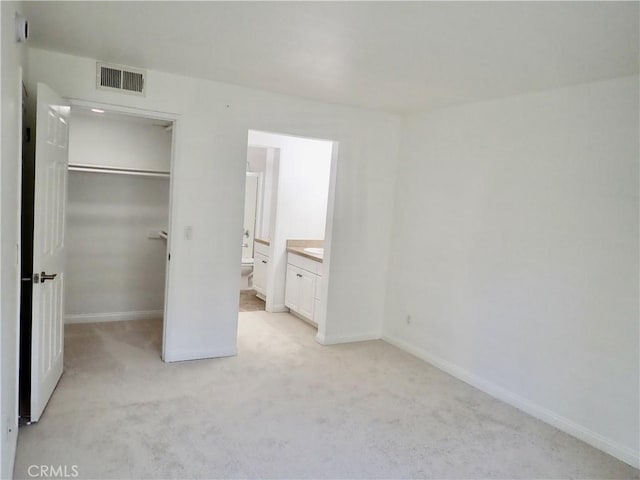 unfurnished bedroom with light carpet, connected bathroom, and a closet