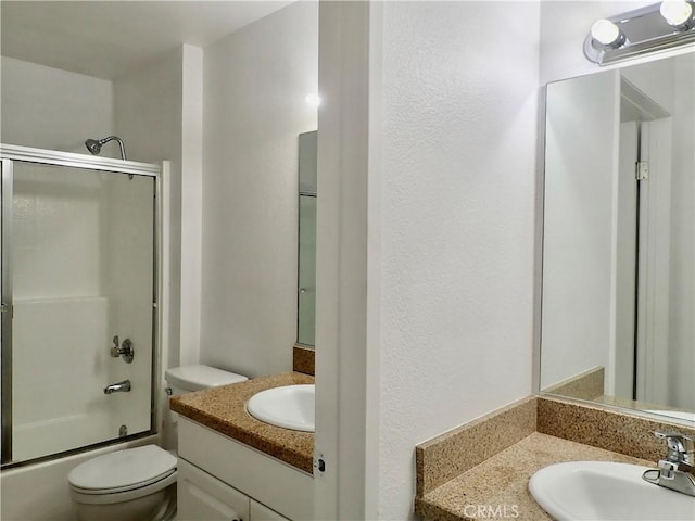 full bathroom with vanity, bath / shower combo with glass door, and toilet